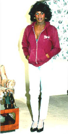 A younger photo of Roberta, posing for the blurry camera in a hot pink track jacket and white jeans with black pumps.